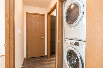 A washing machine is in a small room with a wooden door.